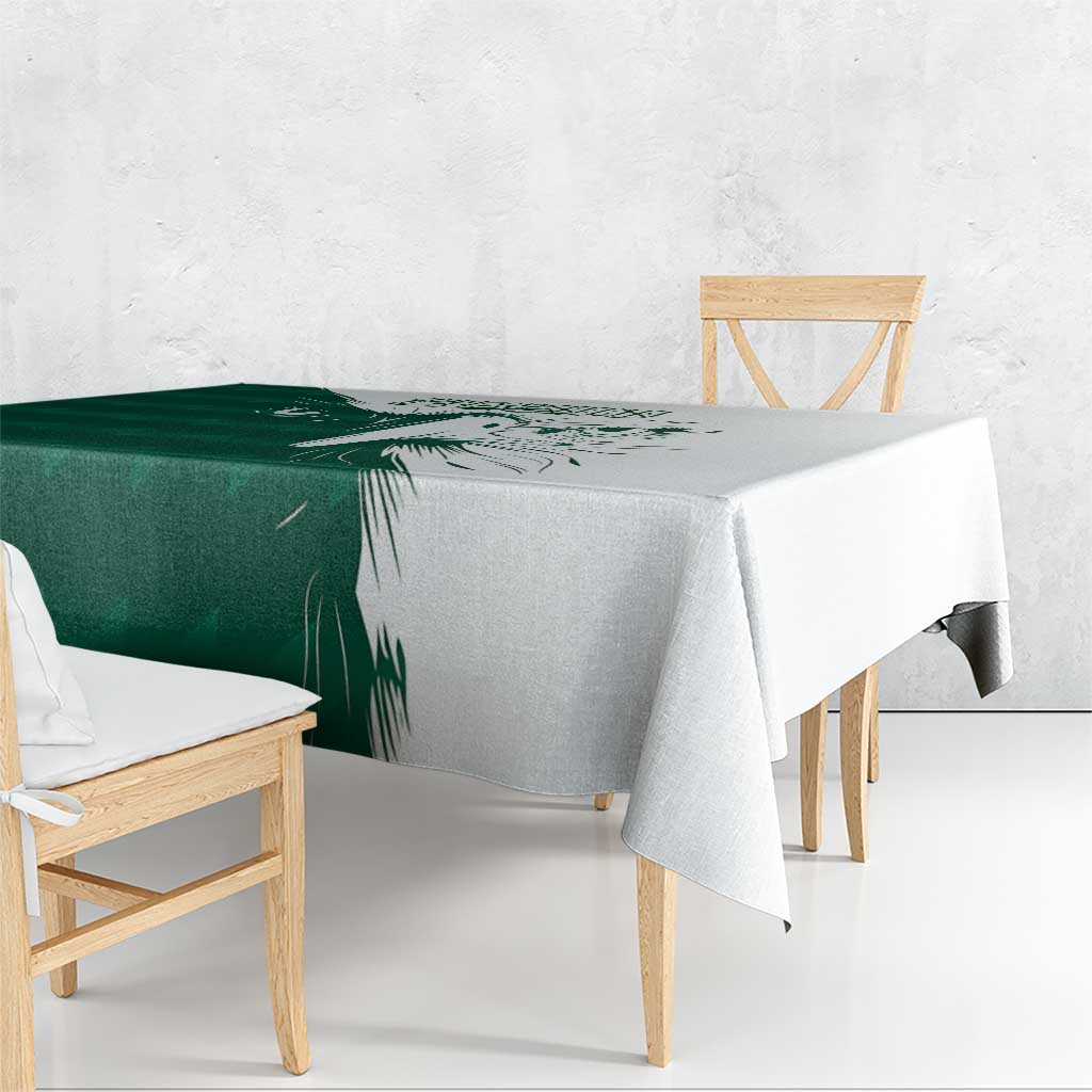 Green and white tablecloth with falcon motif, hanging over bench-style dining table