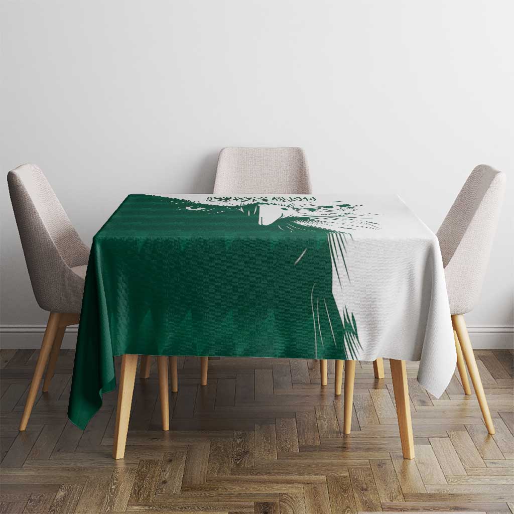 Green and white rectangular tablecloth with falcon graphic and Arabic text on table