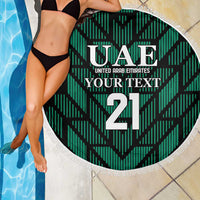 Green circular beach blanket with UAE text and 21 number, white fringe edge beside pool