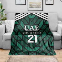 Green football-themed blanket spread on sofa, featuring UAE logo, 'YOUR TEXT', and number 21