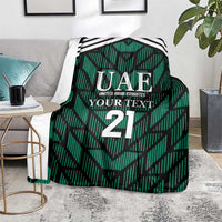 Green football-themed blanket over chair with UAE logo, 'YOUR TEXT', and number 21