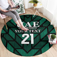 Round green football carpet with UAE crest and large 21, shown being placed