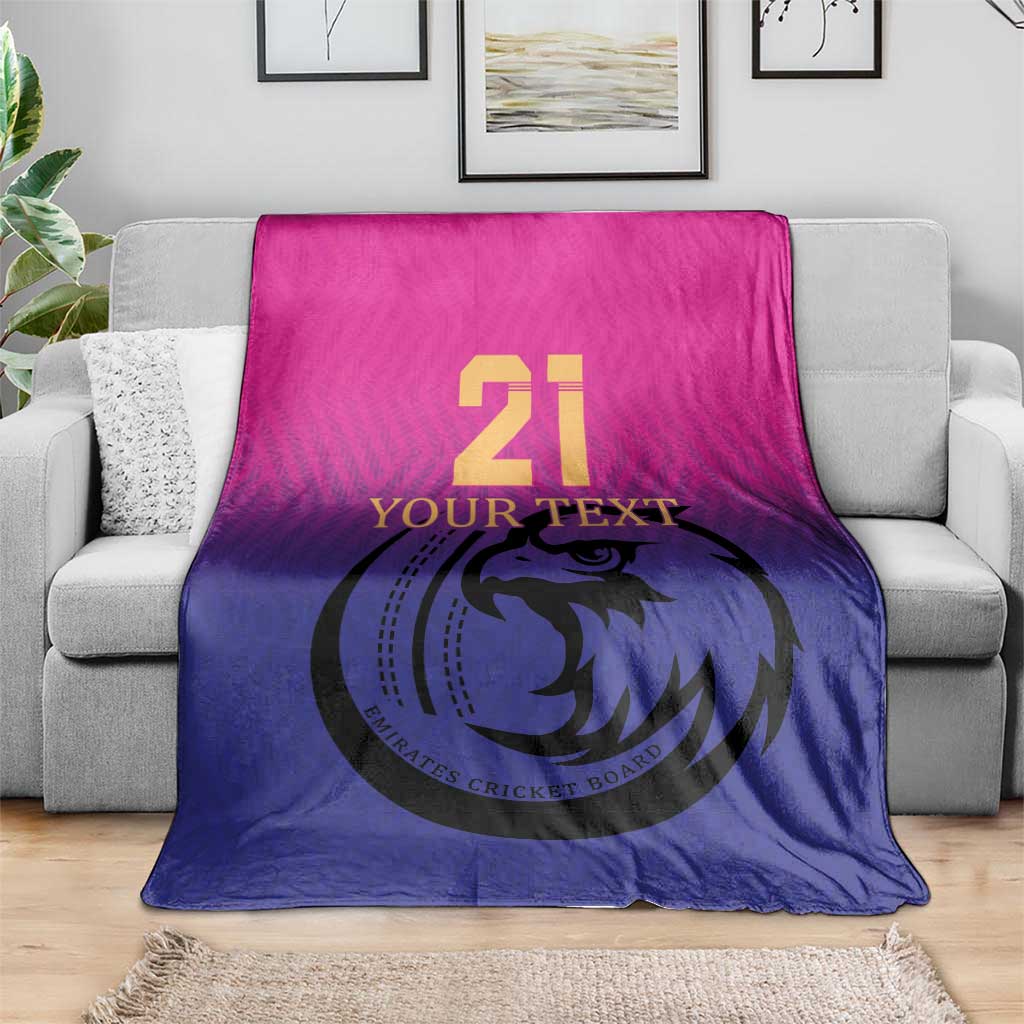 Cricket blanket folded on gray sofa, pink top and blue bottom with falcon 21 print