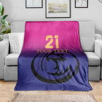 Cricket blanket folded on gray sofa, pink top and blue bottom with falcon 21 print
