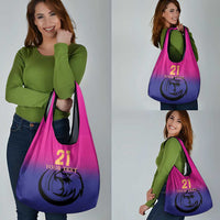 Pink-to-purple gradient tote bag with falcon logo, number 21, carried by shopper