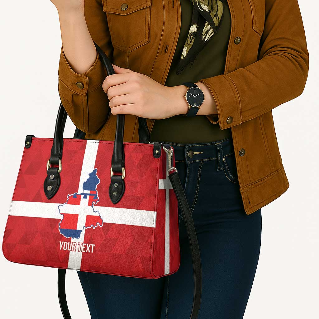 Red-and-white flag print leather tote bag with blue crest and “YOUR TEXT” on front, held by handles