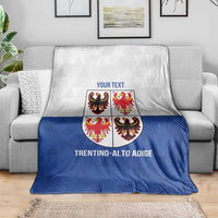 Personalized blue and white blanket draped on sofa with crest shield and region text