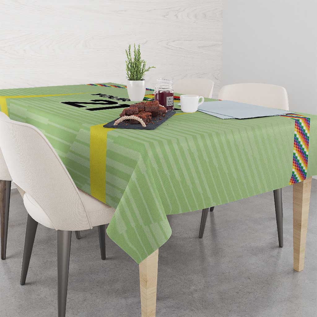 Green soccer tablecloth draped over table with multicolor Wiphala-style edge stripes
