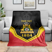 Black/red/yellow personalized throw blanket with crest and “YOUR TEXT”, 1804 on sofa