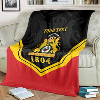 Black/red/yellow personalized throw blanket with crest and “YOUR TEXT”, 1804 on armchair