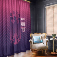 Pink and dark purple football window curtains with glowing crest text near an armchair