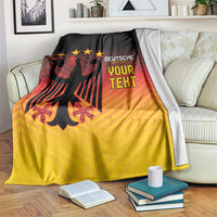 Football blanket draped over sofa, black-red-yellow gradient with eagle and stars, 'YOUR TEXT'