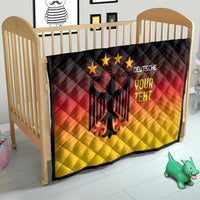 Gradient quilt blanket on a crib with black eagle emblem and “DEUTSCHE YOUR TEXT” design