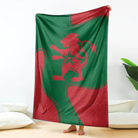 Red and green lion emblem blanket draped over bed with Moroccan flag pattern