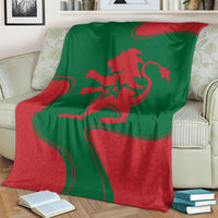 Red and green lion emblem blanket draped over couch with Moroccan flag design