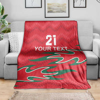 Red custom cricket throw blanket with green pattern and white “YOUR TEXT” over couch