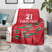 Red cricket blanket draped on chair, with green pattern and white “YOUR TEXT” and 21