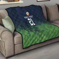 Green and dark blue quilt on couch with custom text, crest logo, and number 21