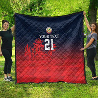 Cricket quilt laid flat outdoors with navy top, red bottom, crest, flame graphic, number 21