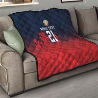 Cricket quilt draped on sofa with navy quilted diamonds, red gradient bottom, crest and 21