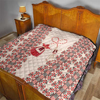 Quilted bedspread in beige with red folk print border and central heart-and-figure motif