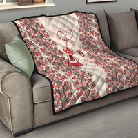 Quilted throw blanket draped on sofa with beige field and red folk stripe border