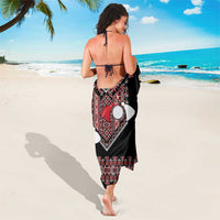 Black sarong draped at back with red and white circular pendant pattern