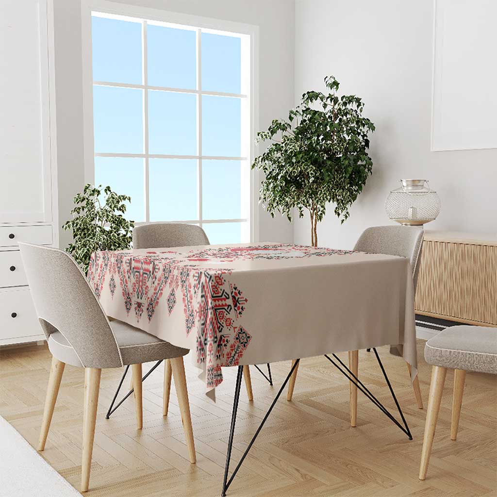 Beige tablecloth with red and navy folk embroidery pattern covering dining table