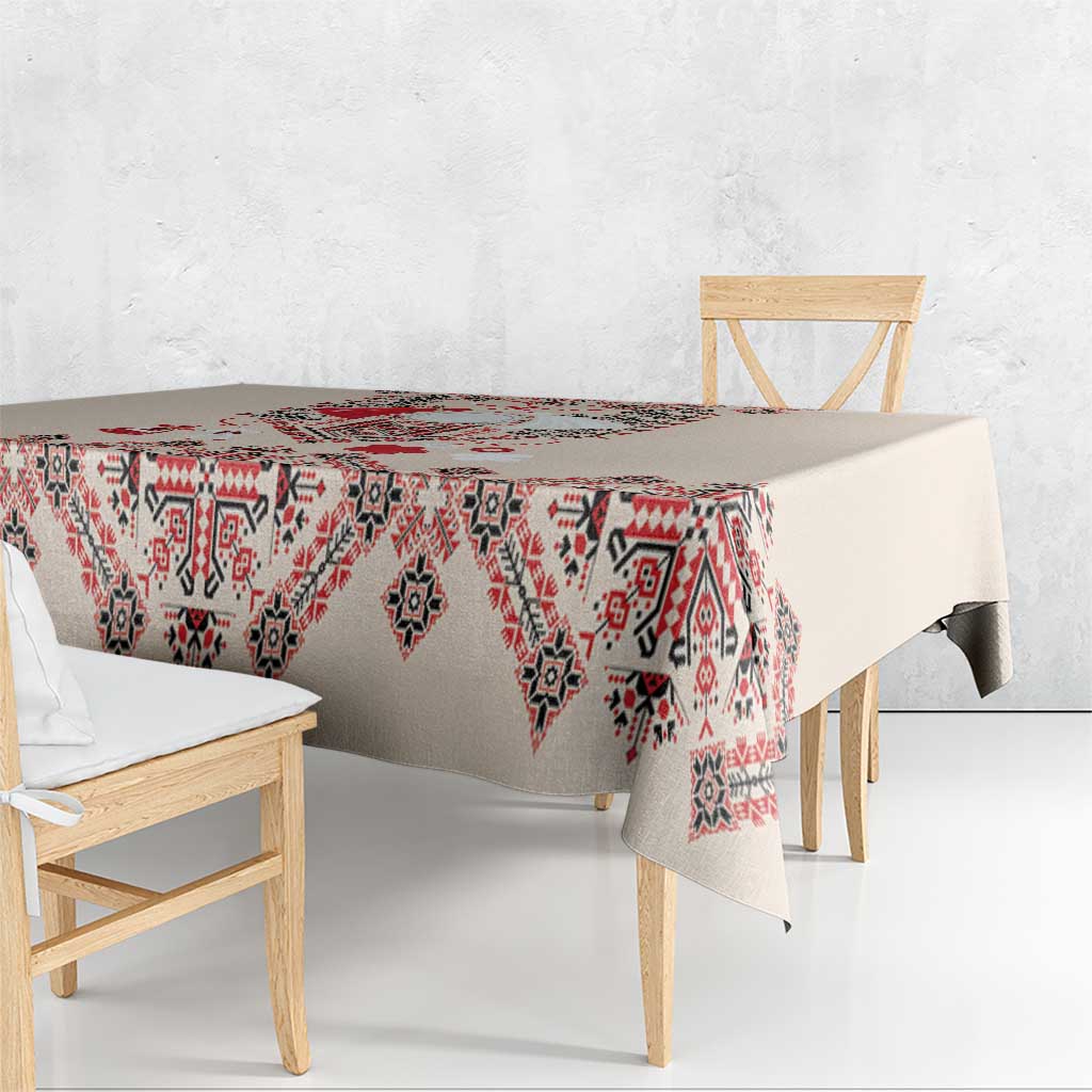 Beige tablecloth with red, navy, and white geometric folk embroidery on hanging edge