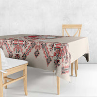 Beige tablecloth with red, navy, and white geometric folk embroidery on hanging edge