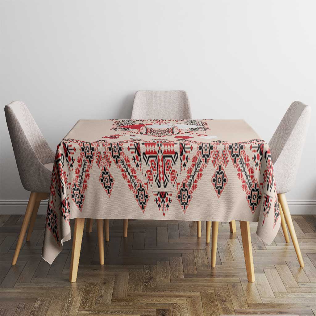 Beige tablecloth with red, navy, and white folk embroidery diamond pattern on dining table