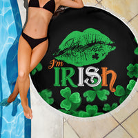 Black round beach blanket showing green lips and 'I'm Irish' typography with clover pattern, fringe