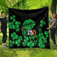 Black quilt blanket with green clovers and Irish-themed center graphic, on grass.