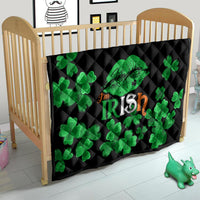 Black quilt in a baby crib with green clovers and Irish-themed center graphic.