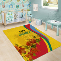 Gold Grenada area rug with 1974 lettering, bougainvillea flowers, and flag-style rainbow swoosh