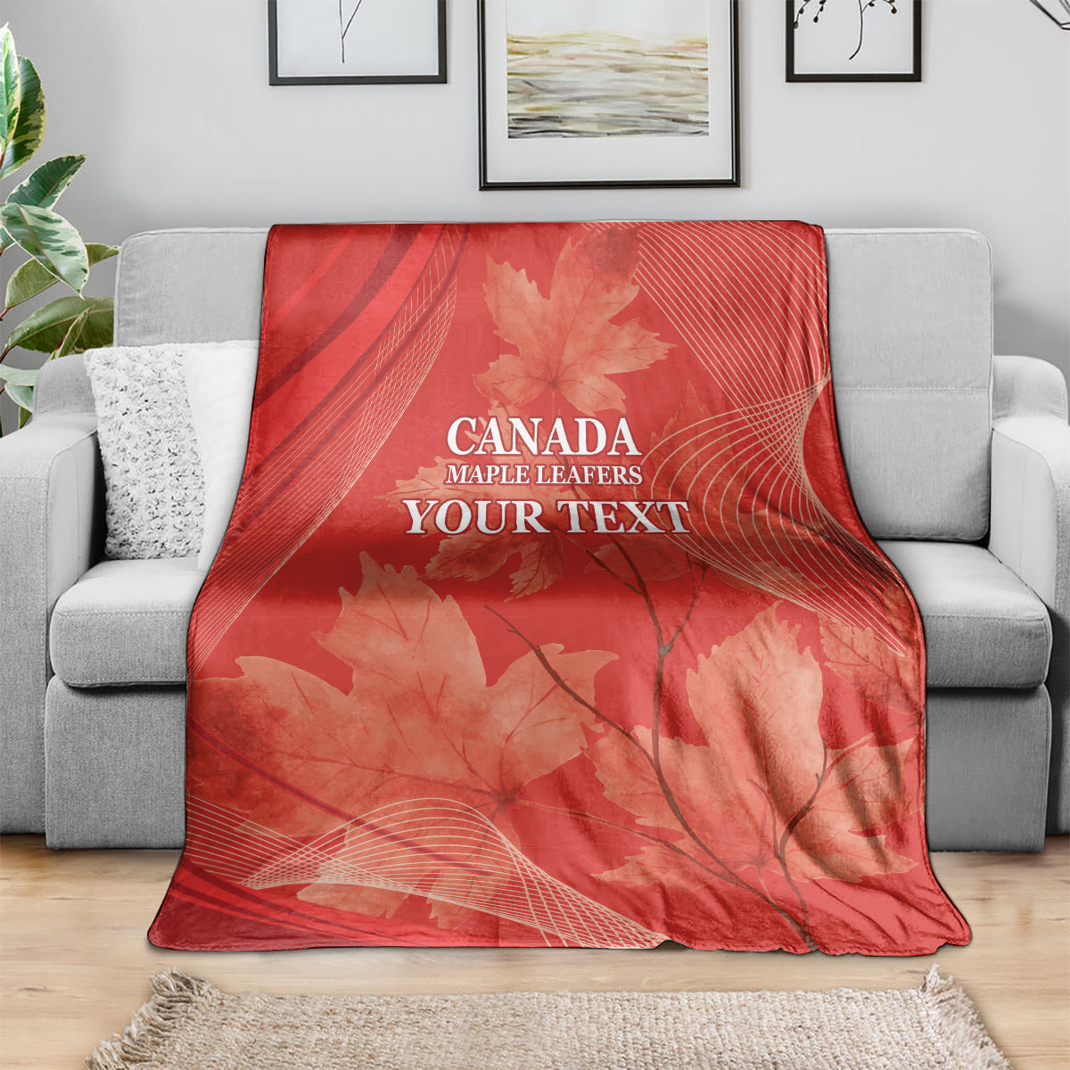Red Canada Maple Leafs blanket draped over gray sofa, maple leaves and 'YOUR TEXT'