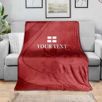 Red cricket blanket with white emblem and 'YOUR TEXT' laid on a gray sofa