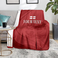 Red cricket blanket with white England emblem and 'YOUR TEXT' on a gray sofa