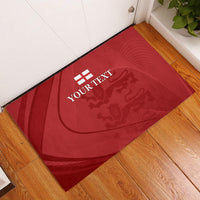 Red rubber doormat with YOUR TEXT and lion crest design, placed on wood floor