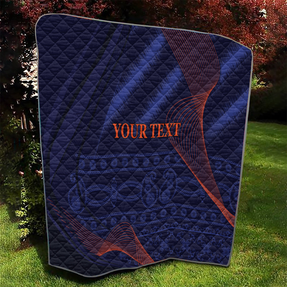 Blue quilt with quilted grid pattern, red swirl accents, “YOUR TEXT” in center