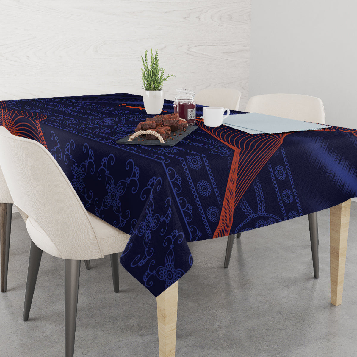 Blue tablecloth draped on dining table with orange-red swirls and dark floral pattern