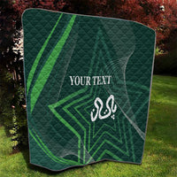 Green quilt folded on grass with diamond quilting, white “YOUR TEXT” and emblem