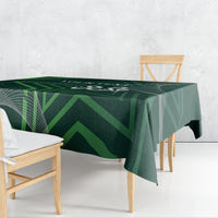 Green patterned tablecloth with geometric design and corner drape on wooden table
