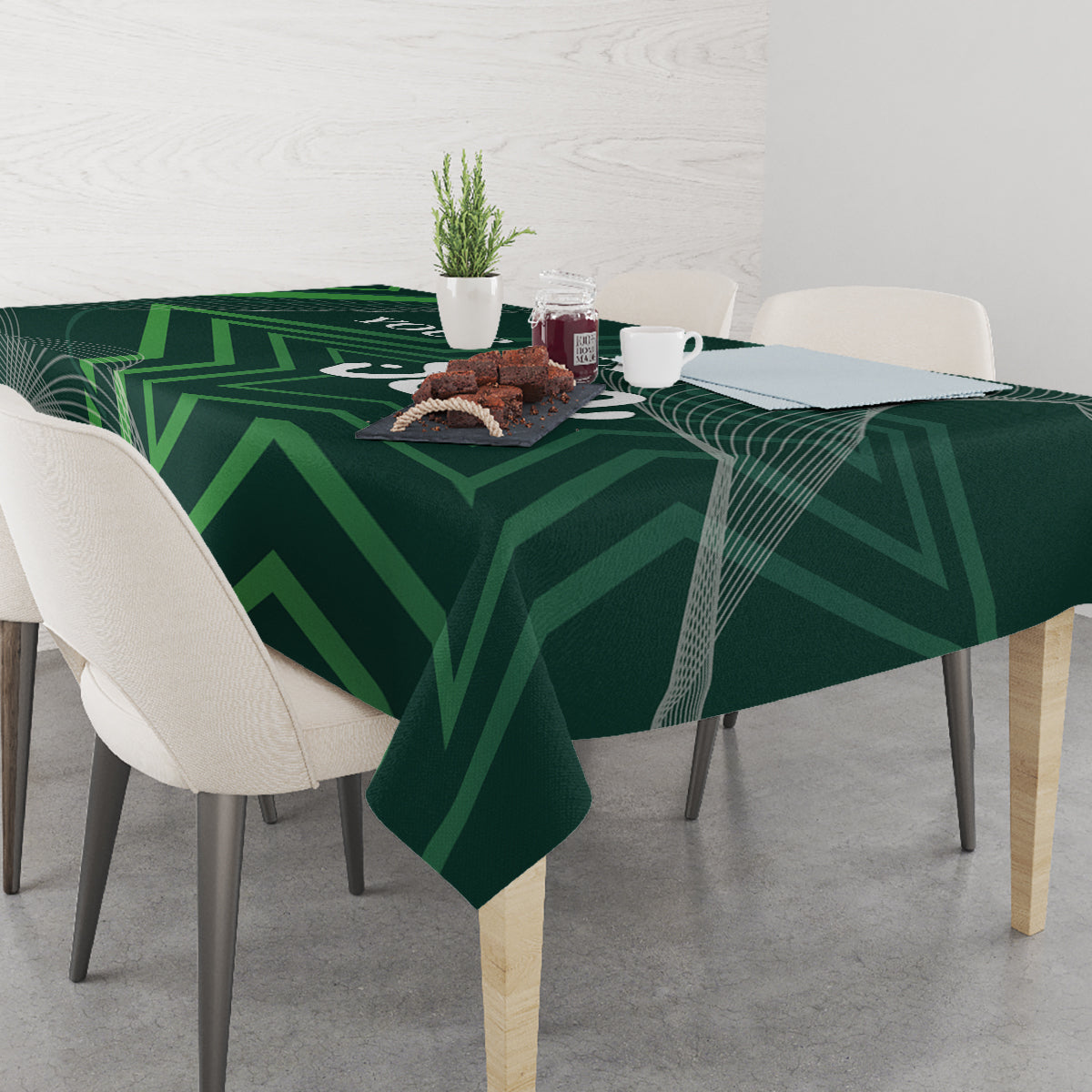 Green tablecloth with geometric pattern over dining table with cups and food