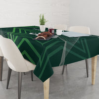 Green tablecloth with geometric pattern over dining table with cups and food