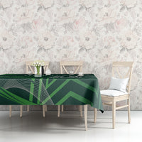 Green geometric tablecloth draped over dining table with plates and cups