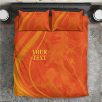 Orange bedding set photographed from above: duvet and 2 pillowcases with 'YOUR TEXT'.