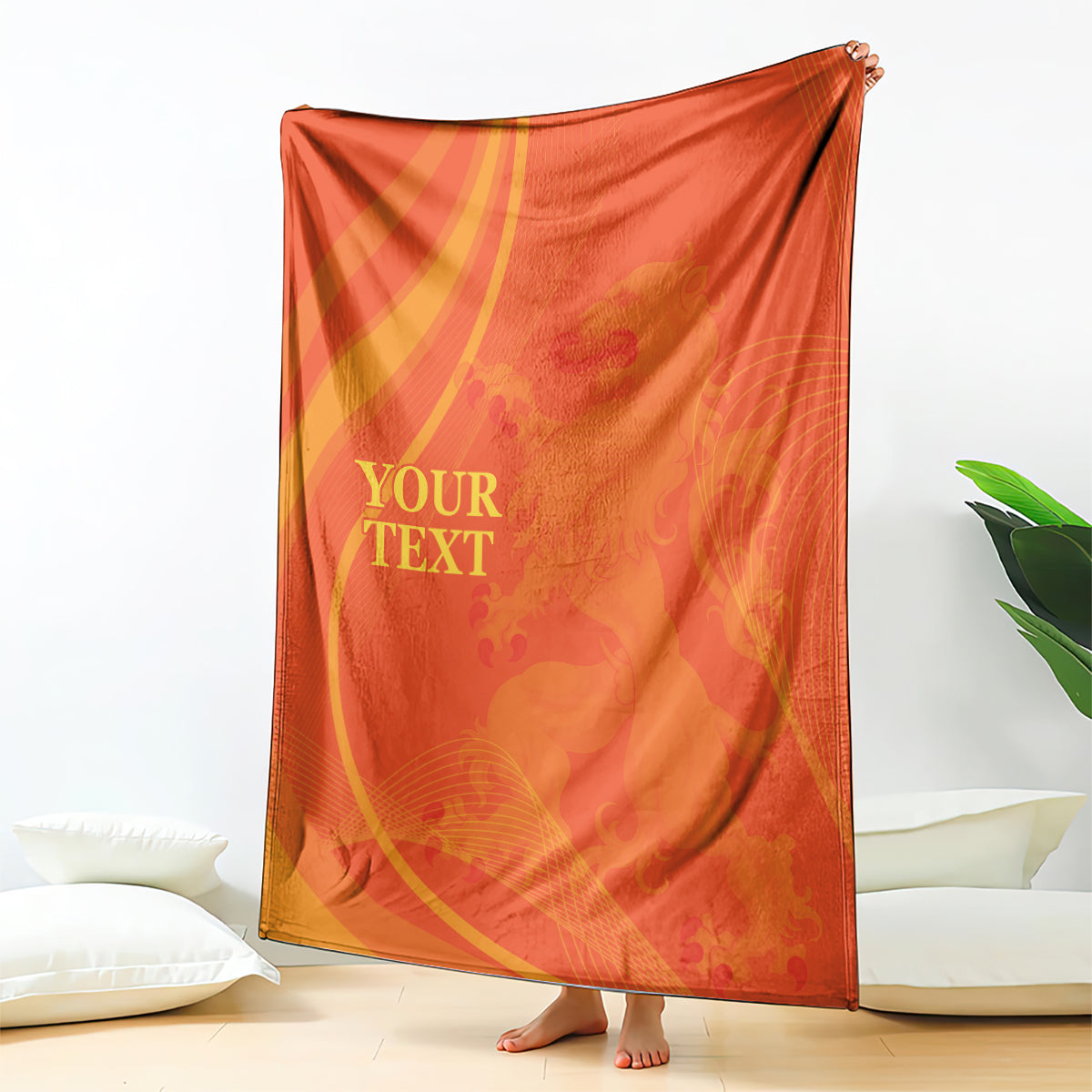 Orange blanket with gold arcs and custom text, standing upright on the floor