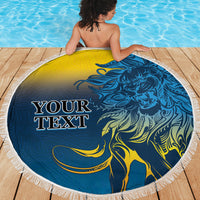 Round beach blanket with blue-and-yellow lion design and white fringed border on deck
