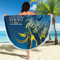 Round beach blanket with lion artwork in blue and yellow, fringed edge held outdoors